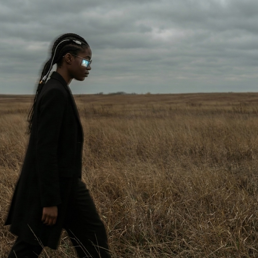 A woman in smart glasses looks across a grassland — seeing ahead.